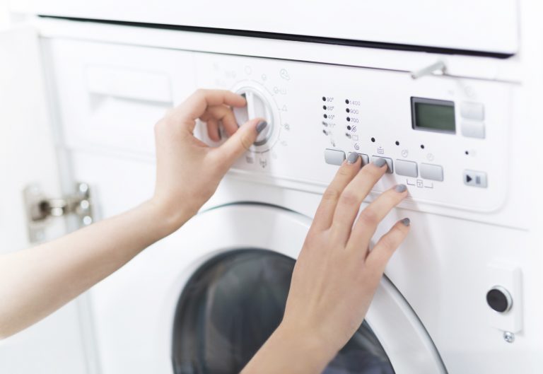 Woman pushing buttons on integrated washing machine - Domex Ltd