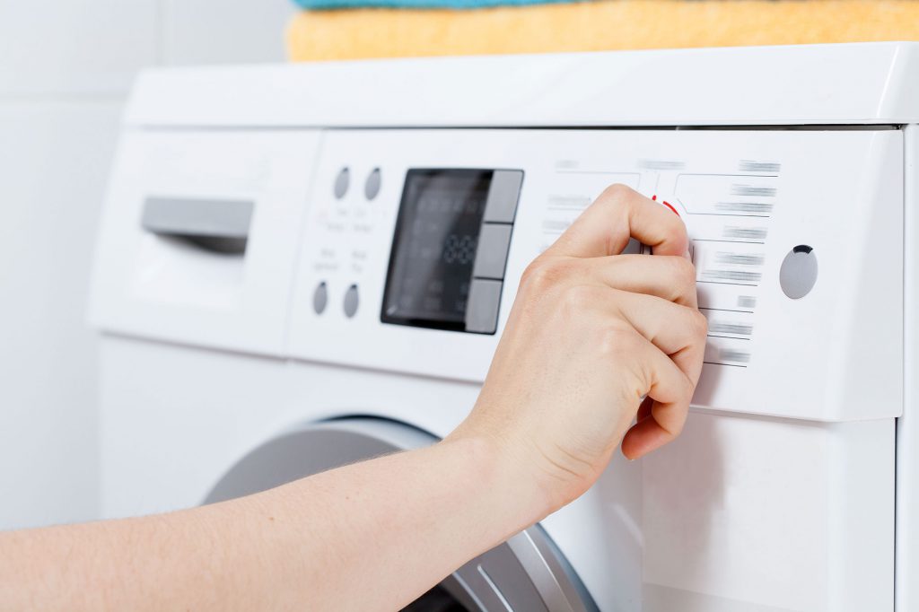 Woman's hand selecting spin cycle on a white washing machine