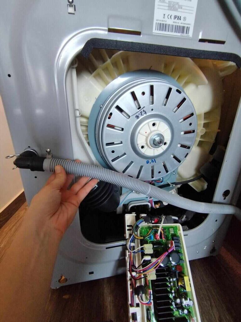 A technician is troubleshooting a washing machine and inspecting the washing machine hose