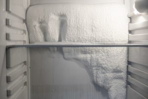 close-up view of thick ice and frost covering the back wall of a freezer