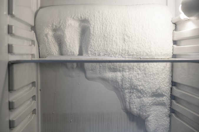 close-up view of thick ice and frost covering the back wall of a freezer