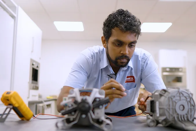 Domex engineer using a multimeter to test washing machine motors before deciding whether to repair or replace